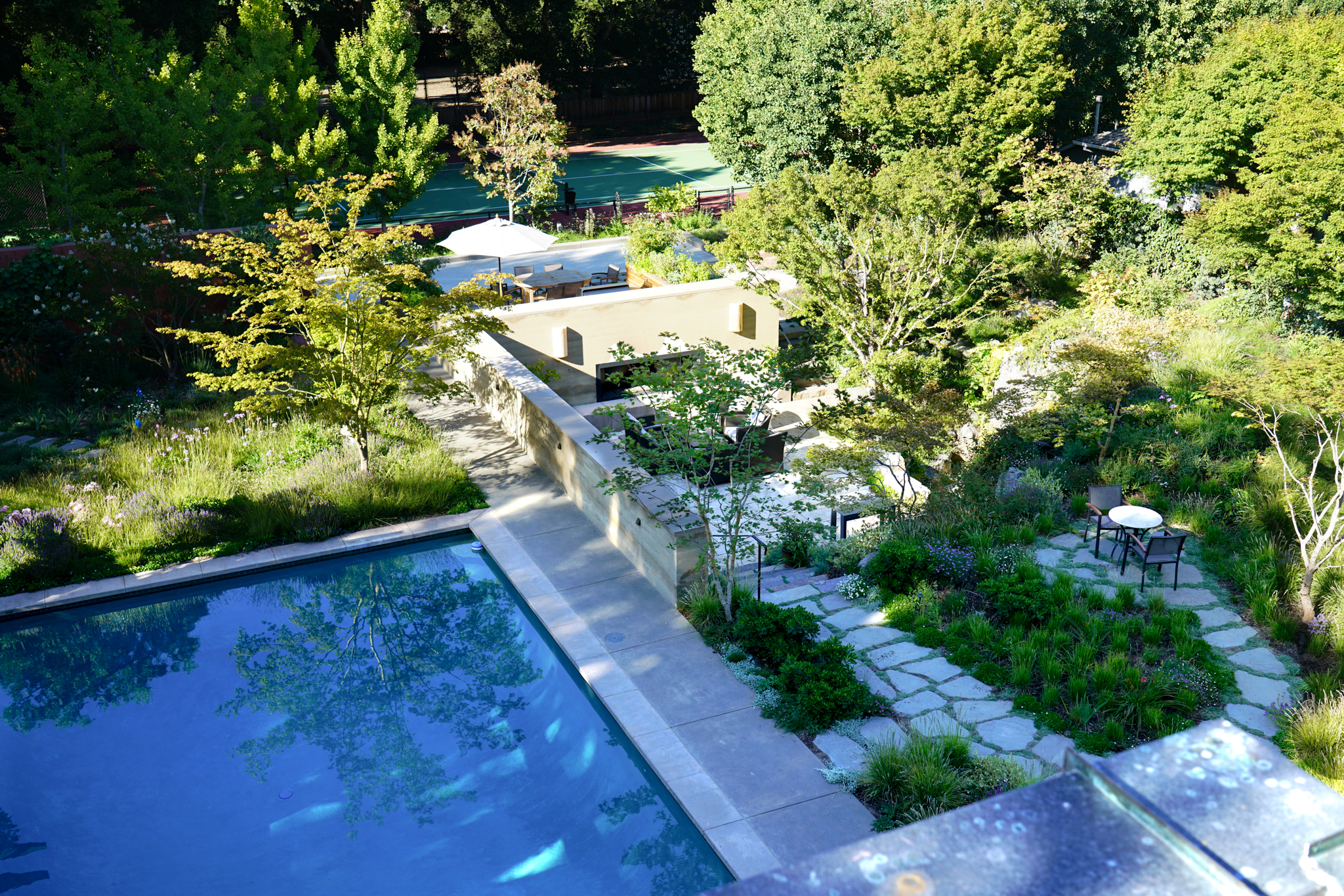 An overhead shot of the garden shows the garden around the pool with a winding path leading to an outdoor seating area.