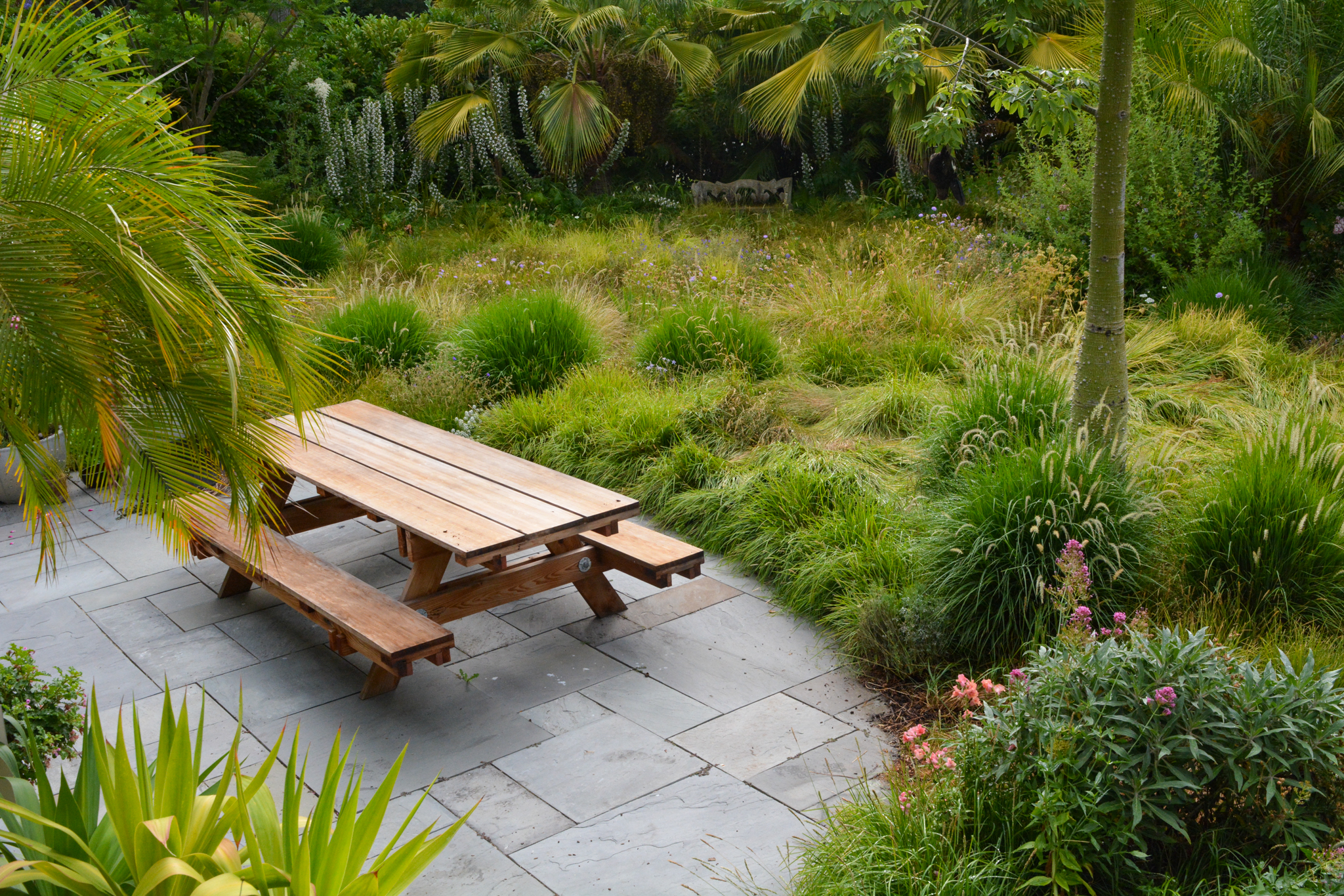 A wooden picnic table sitting at the edge of the garden.